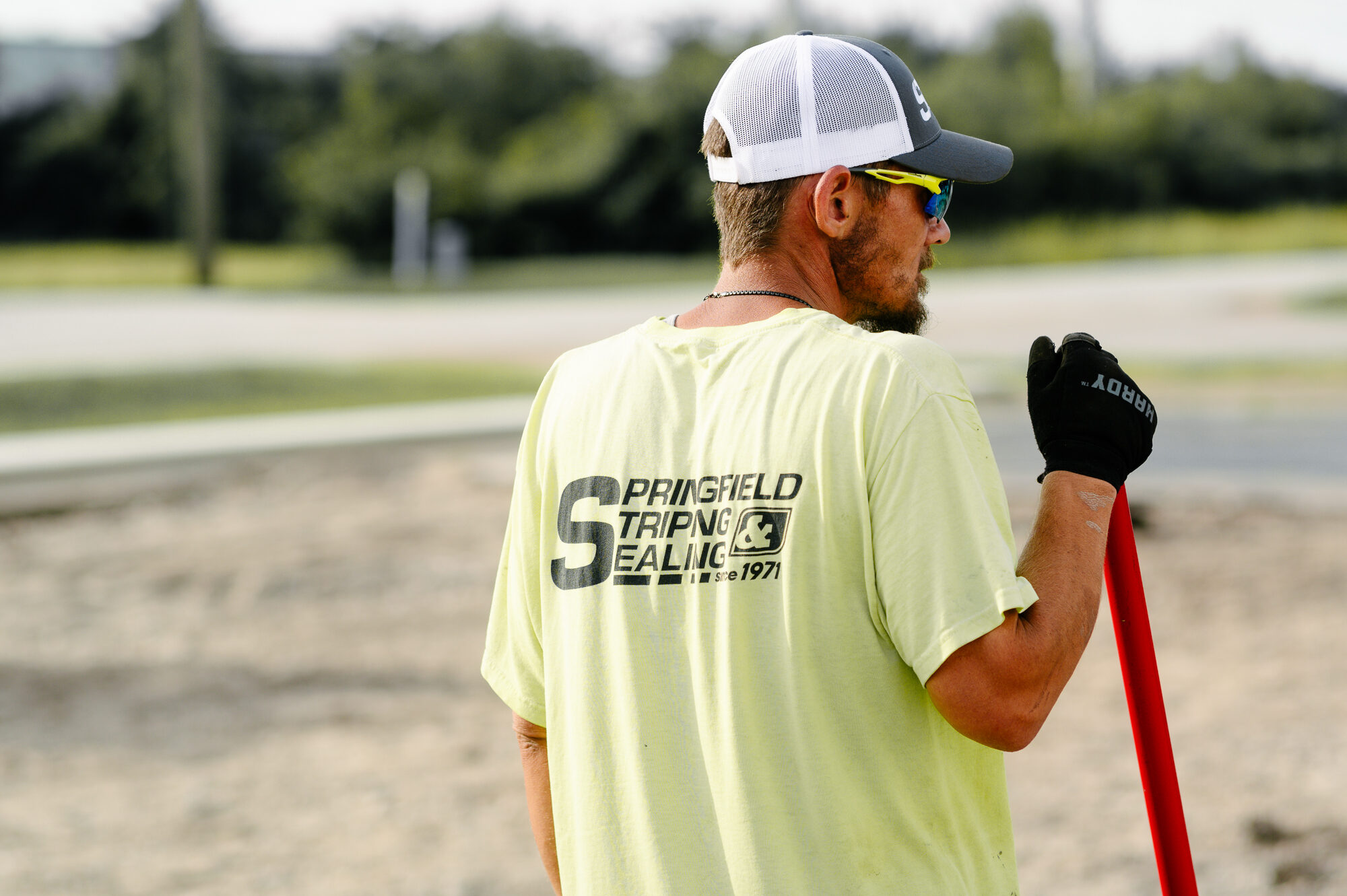 Man in yellow Springfield Striping & Sealing shirt holds tool.