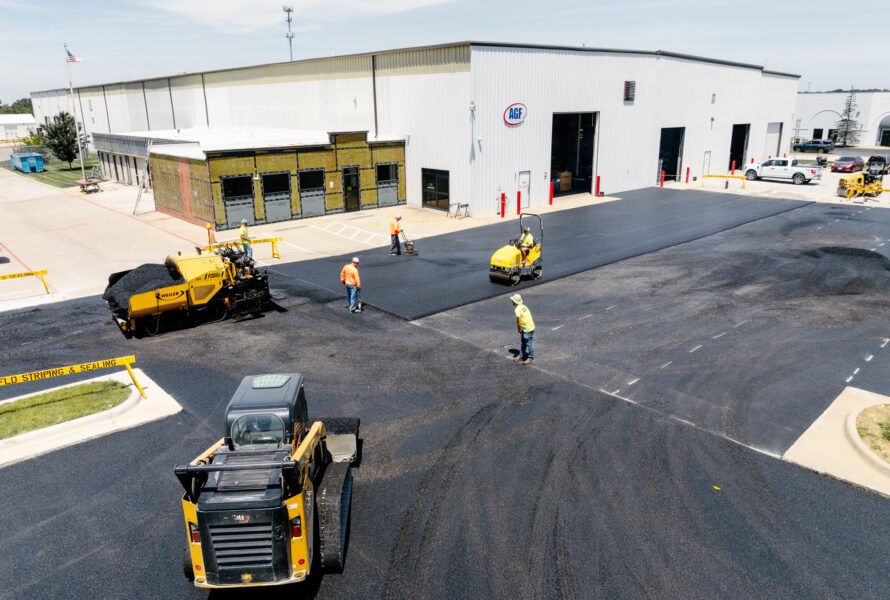 Workers pave parking lot in front of white AGF warehouse.