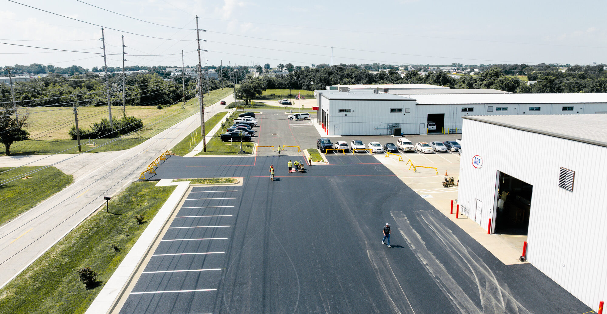 Workers pave parking lot in front of white AGF warehouse.
