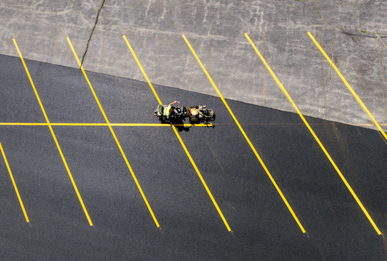 Worker striping yellow lines on new lot, top view.