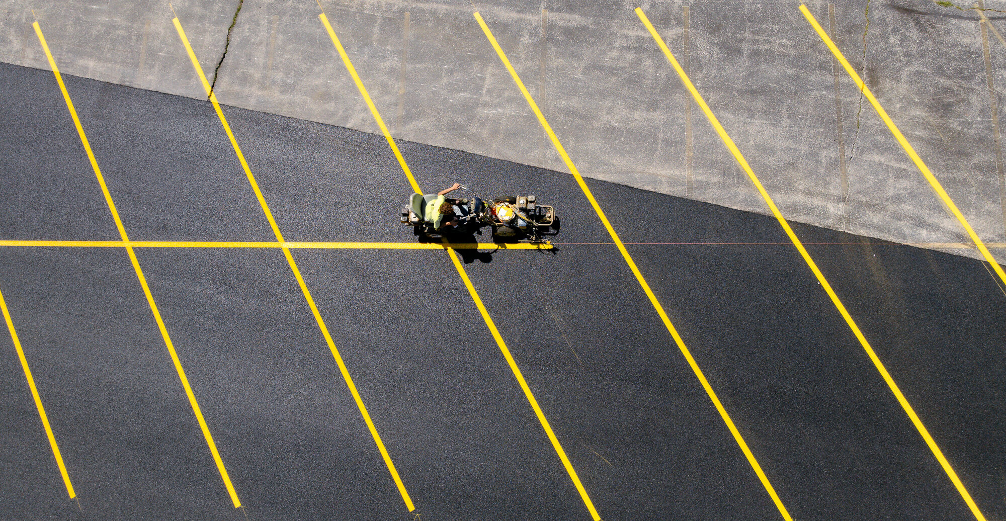 Worker striping yellow lines on new lot, top view.