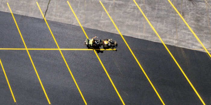 Worker striping yellow lines on new lot, top view.
