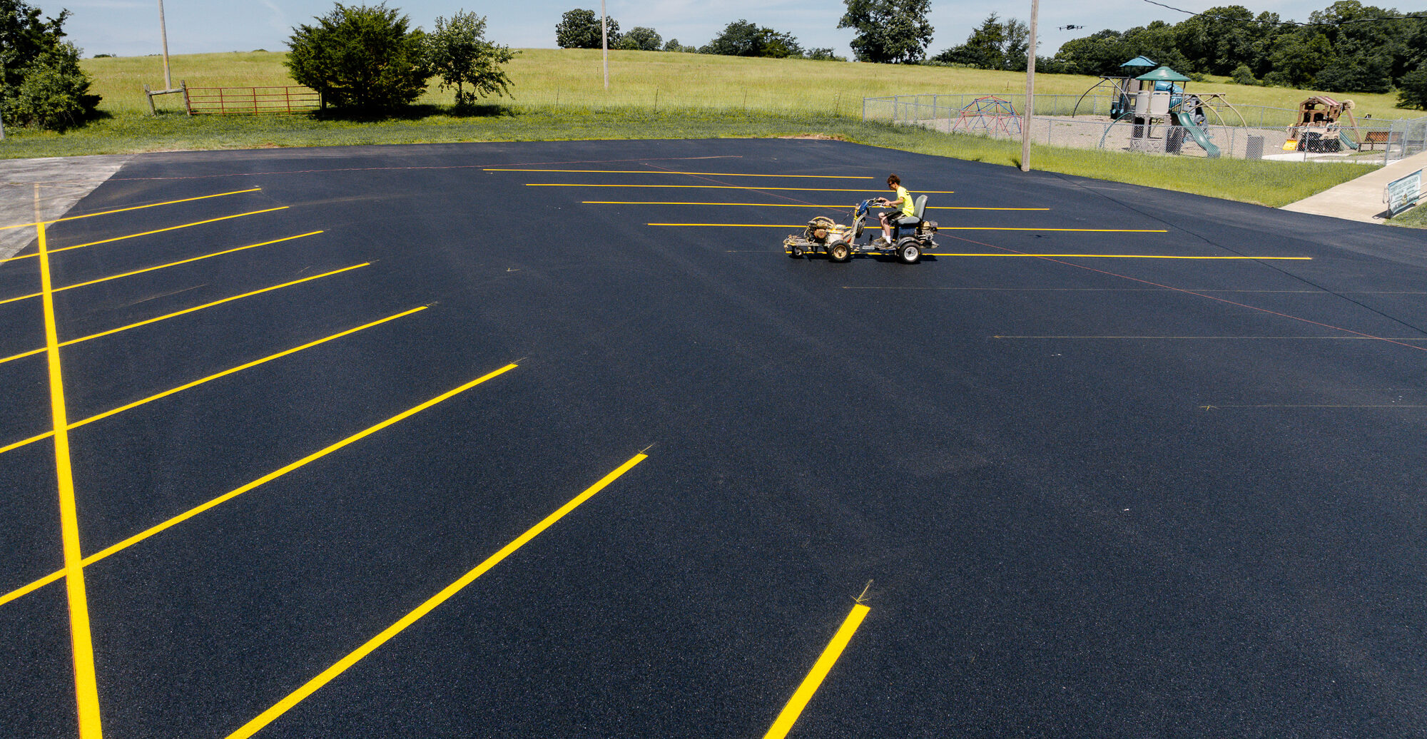 Worker striping yellow lines on new lot, top view.