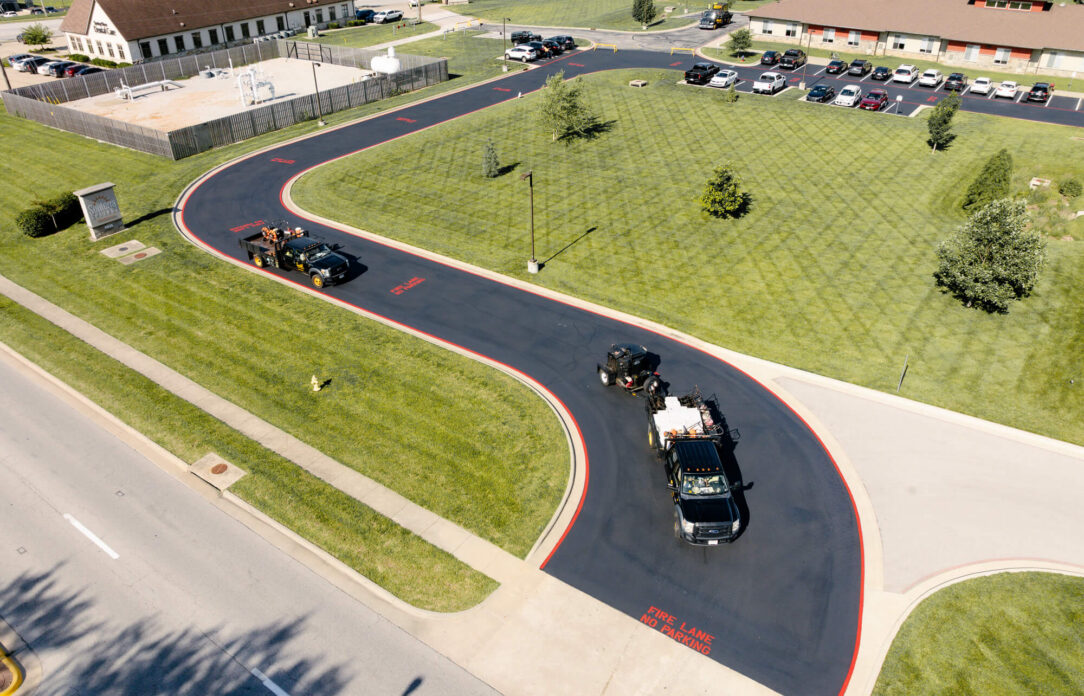 Aerial view of driveway resurfacing near parking lot and grass.
