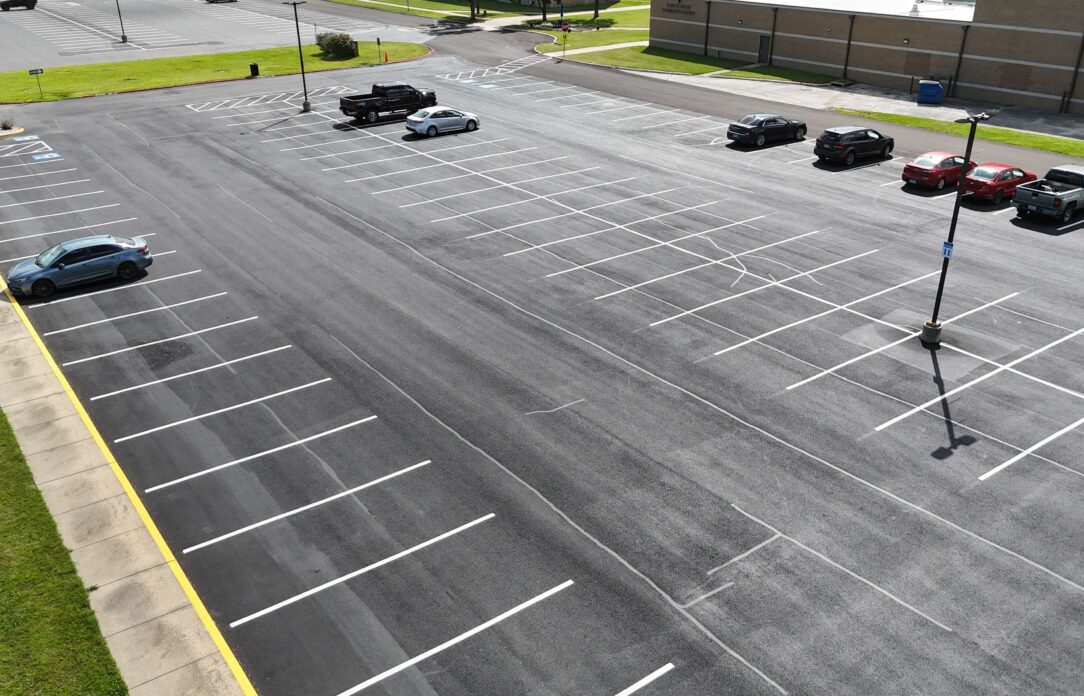 Nearly empty lot with a few cars near a building.