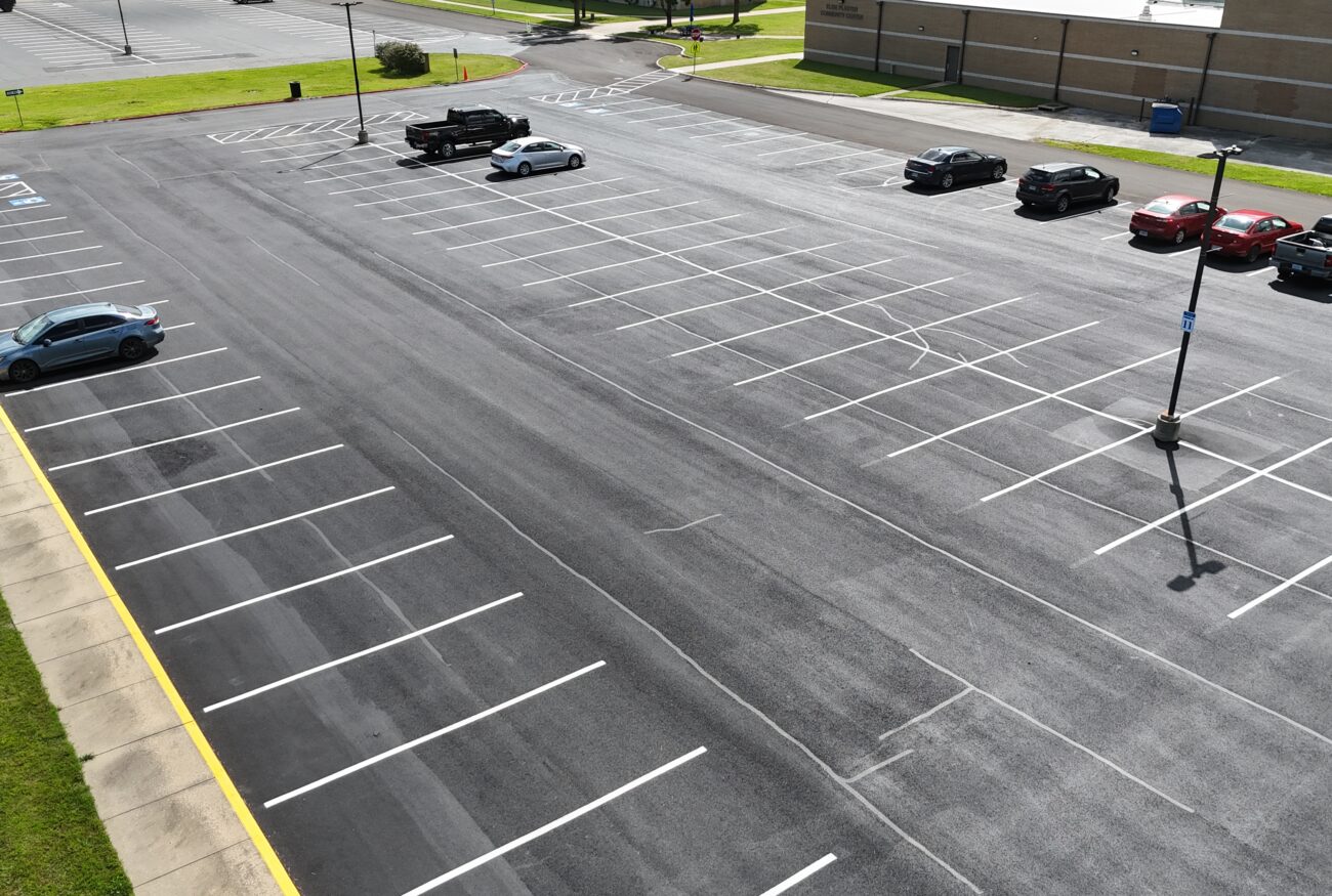 Aerial view of cars in lined asphalt parking lot.