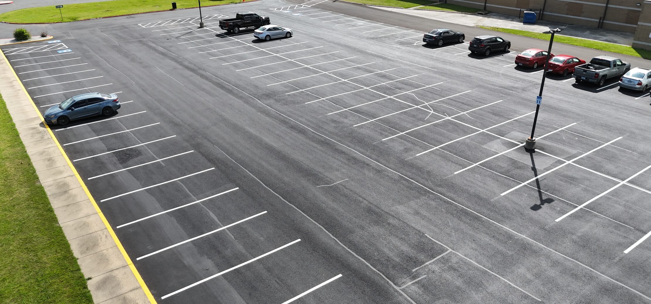 Aerial view of cars in lined asphalt parking lot.
