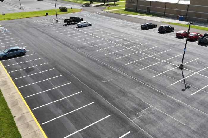 Aerial view of cars in lined asphalt parking lot.
