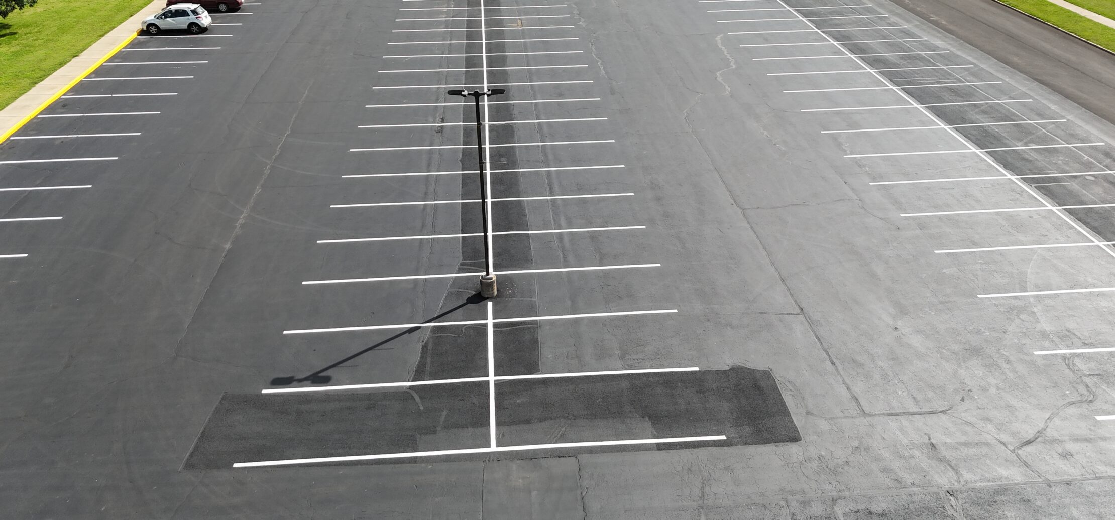 Aerial view of cars in lined asphalt parking lot.