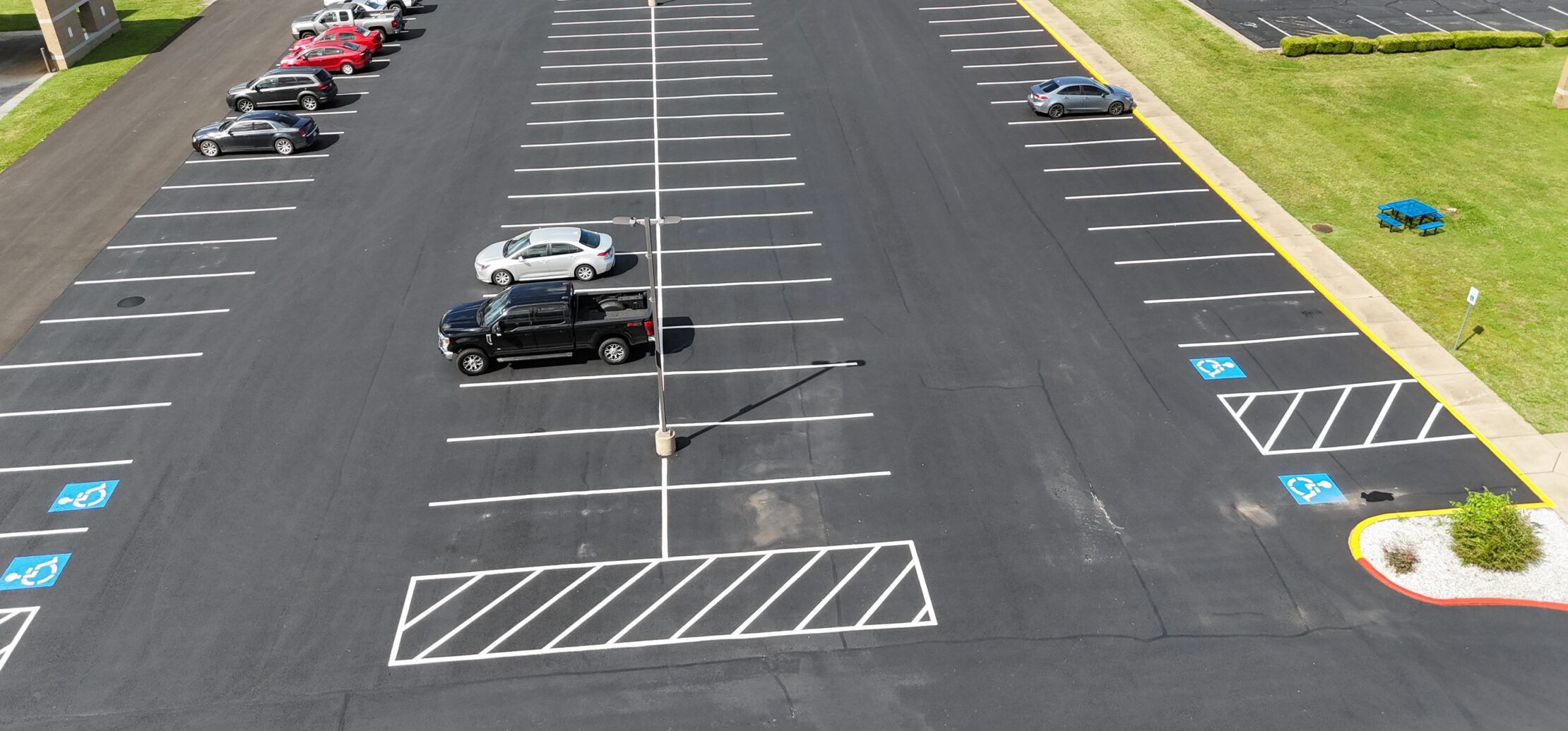 Aerial view of cars in lined asphalt parking lot.
