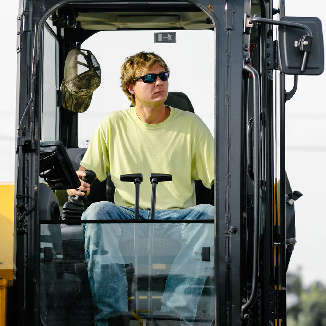 Man in yellow shirt operates heavy machinery.