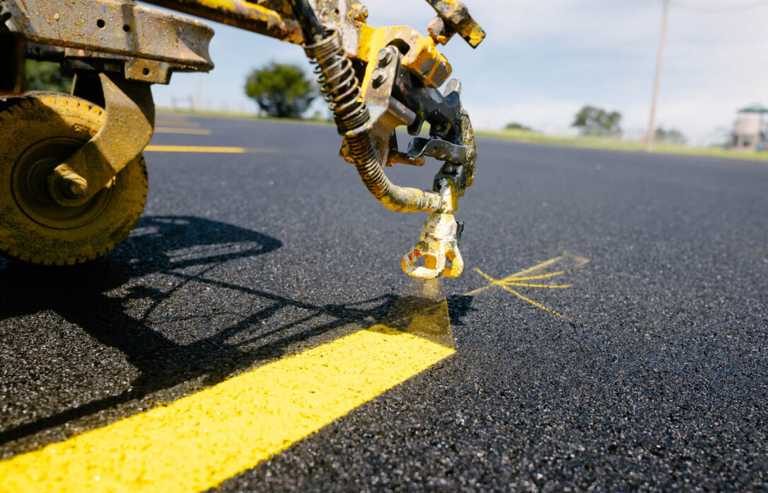 Machine painting a yellow line on new asphalt.