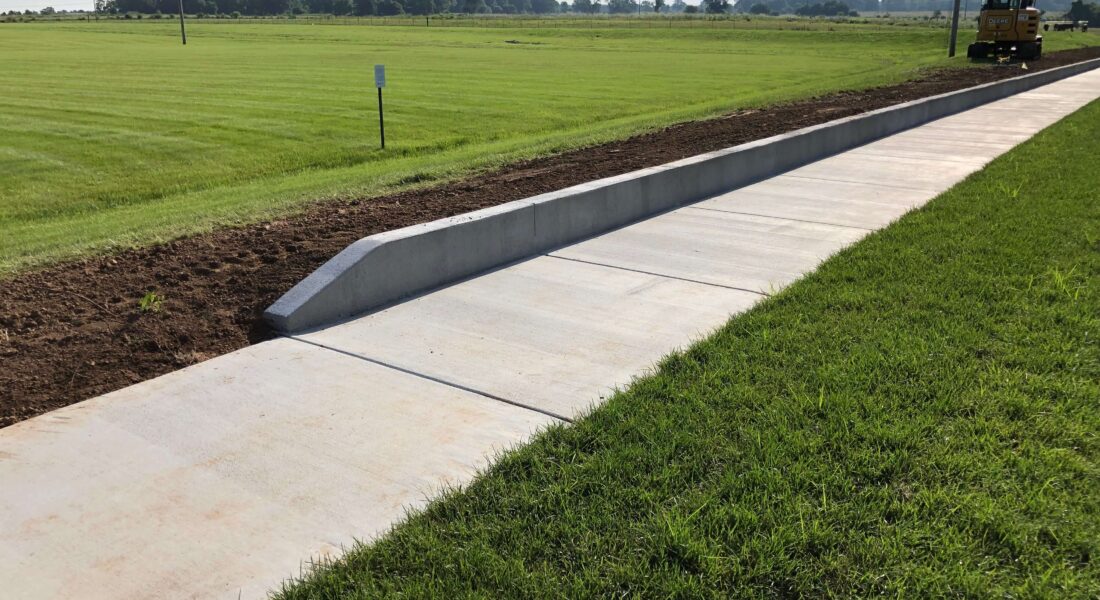 A new sidewalk surrounded by green grass.