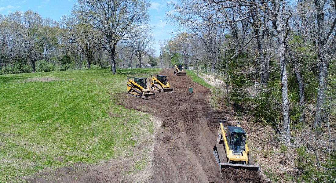 Equipment clearing land next to some trees.