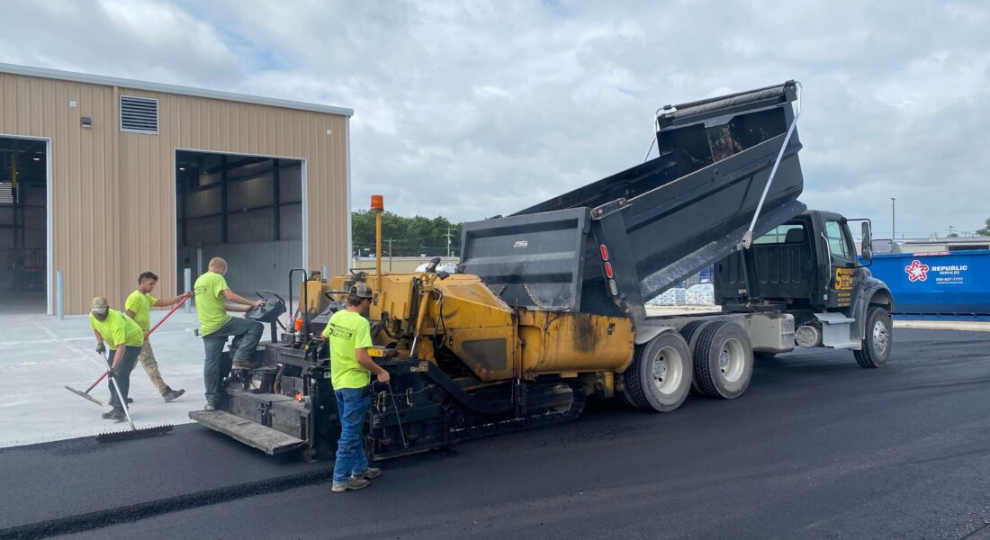 Team of workers lay hot asphalt.