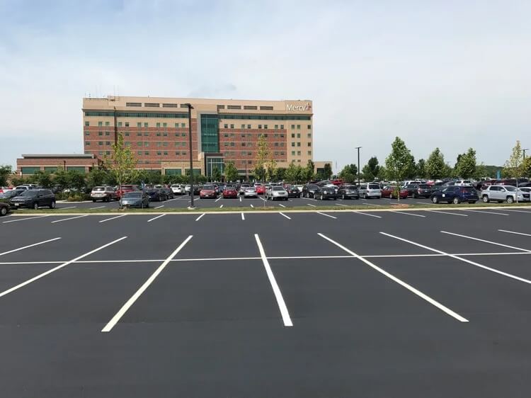 A full parking lot in front of a hospital.