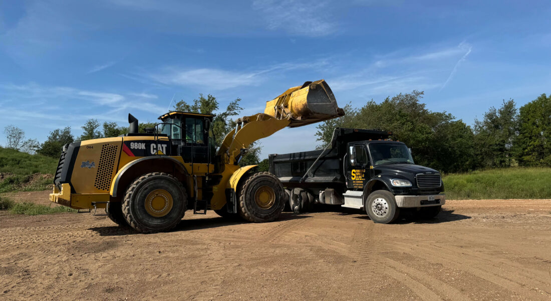 Springfield Striping and Sealing truck and excavation equipment on a dirt lot with blue skies.