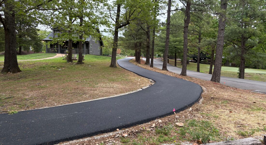 New black asphalt leads up to a wood cabin.