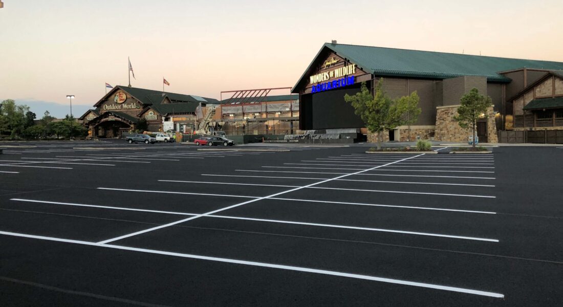 A newly painted parking lot in front of a Bass Pro Shop with white parking spots.