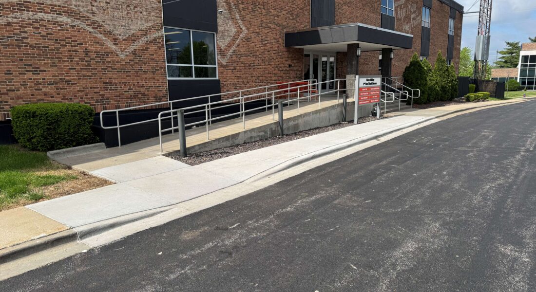 New concrete walkway in front of a handicapped ramp.