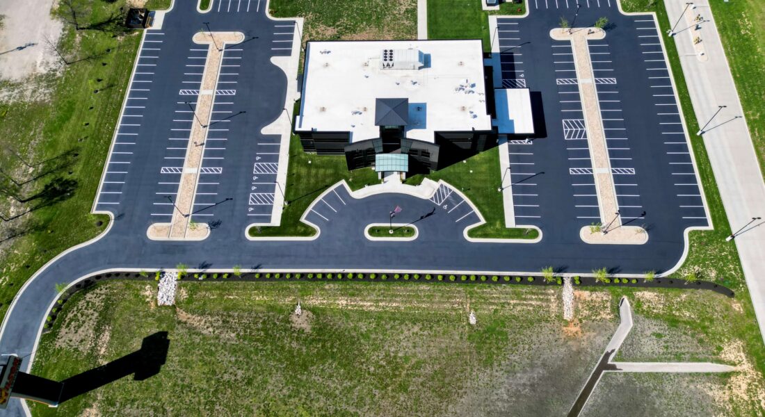 A parking lot that with newly laid asphalt and white striped parking spots.