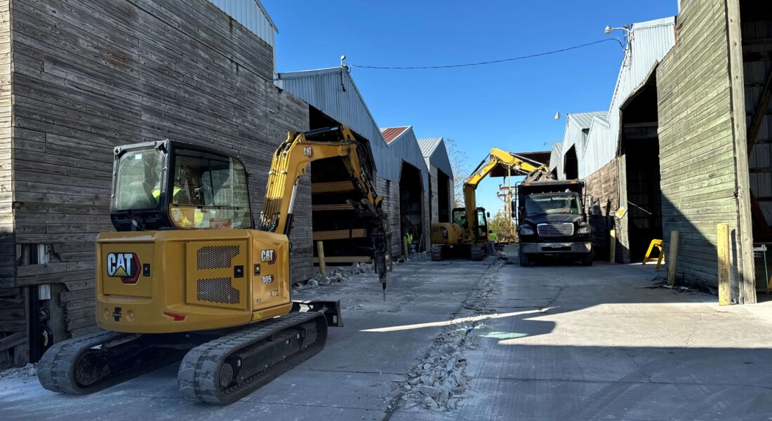 Yellow excavators and equipment work on demolishing an alleyway.