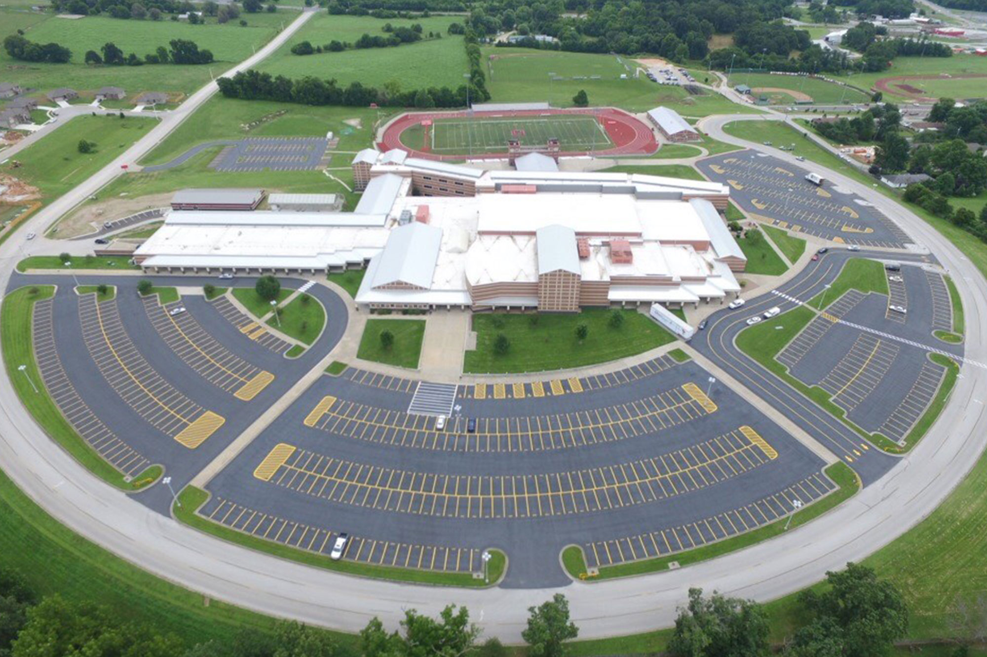 Aerial view of school, parking lots, fields, and greenery.